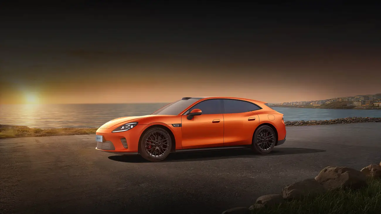 Orange AISTALAND GT7 driving along the coast at sunset